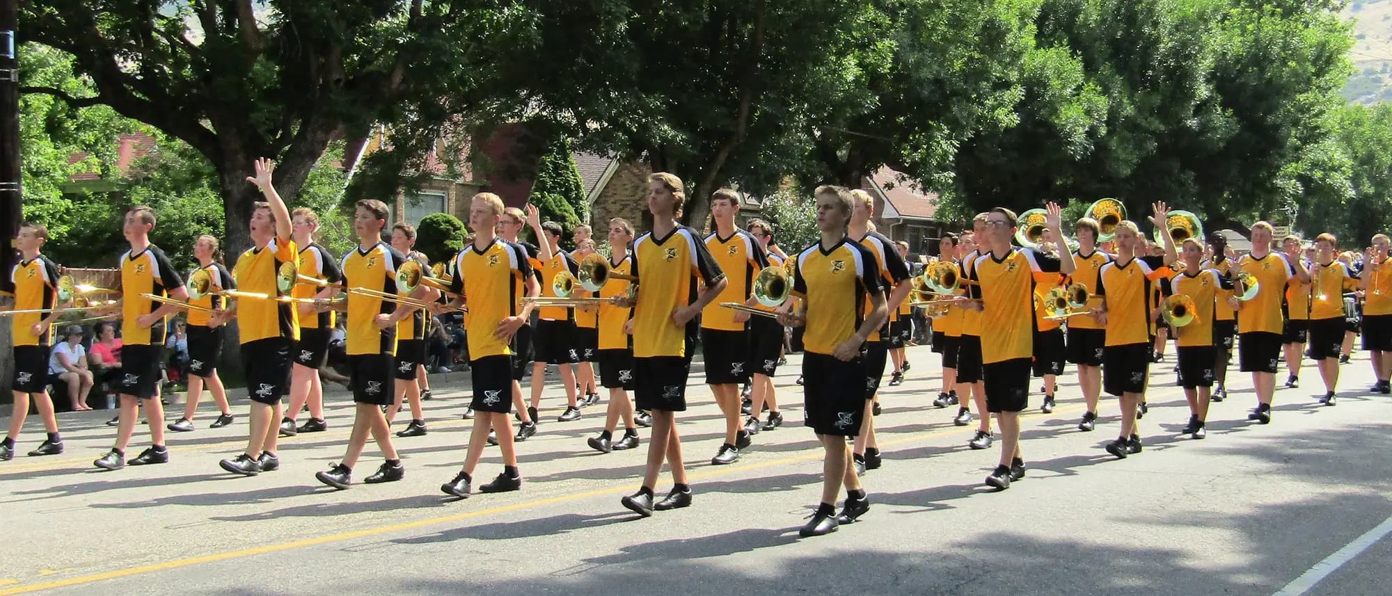 The Davis High School marching band playing in a street parade, brass section in front.