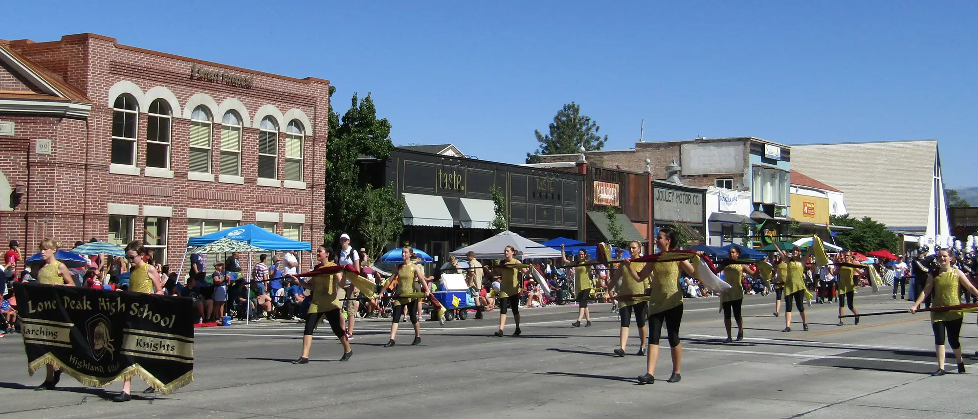 The Lone Peak High School marching band moving down a parade route in uniform.